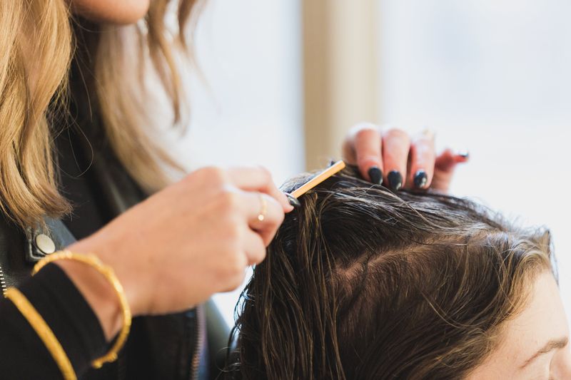 Hair stylist combing hair of client with brunette hair